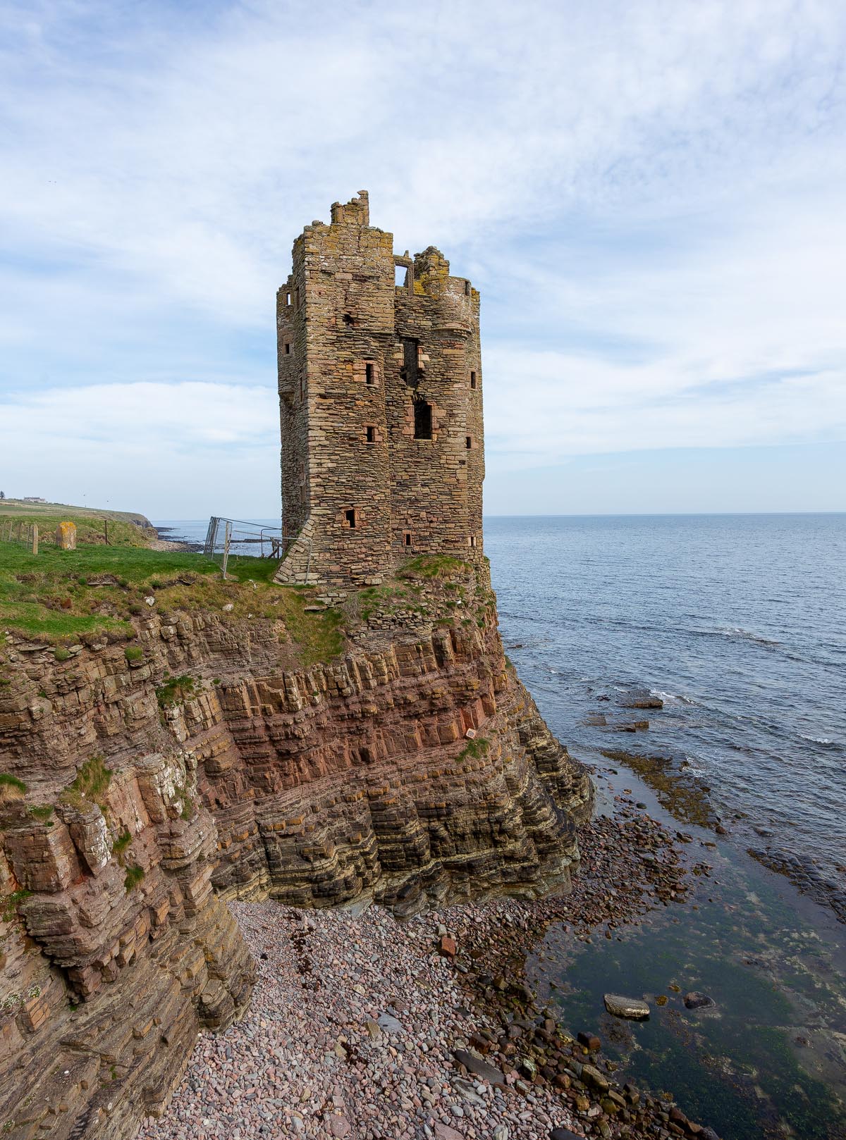 Old Keiss Castle tower rising dramatically from layered sandstone cliffs above the North Sea in Caithness