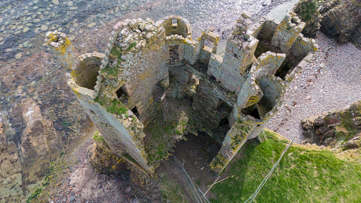 Drone view looking directly down into the roofless interior of Old Keiss Castle showing the internal layout