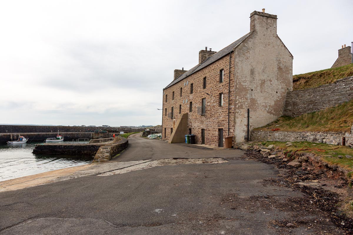 Keiss Harbour with historic three-storey warehouse building and fishing boats