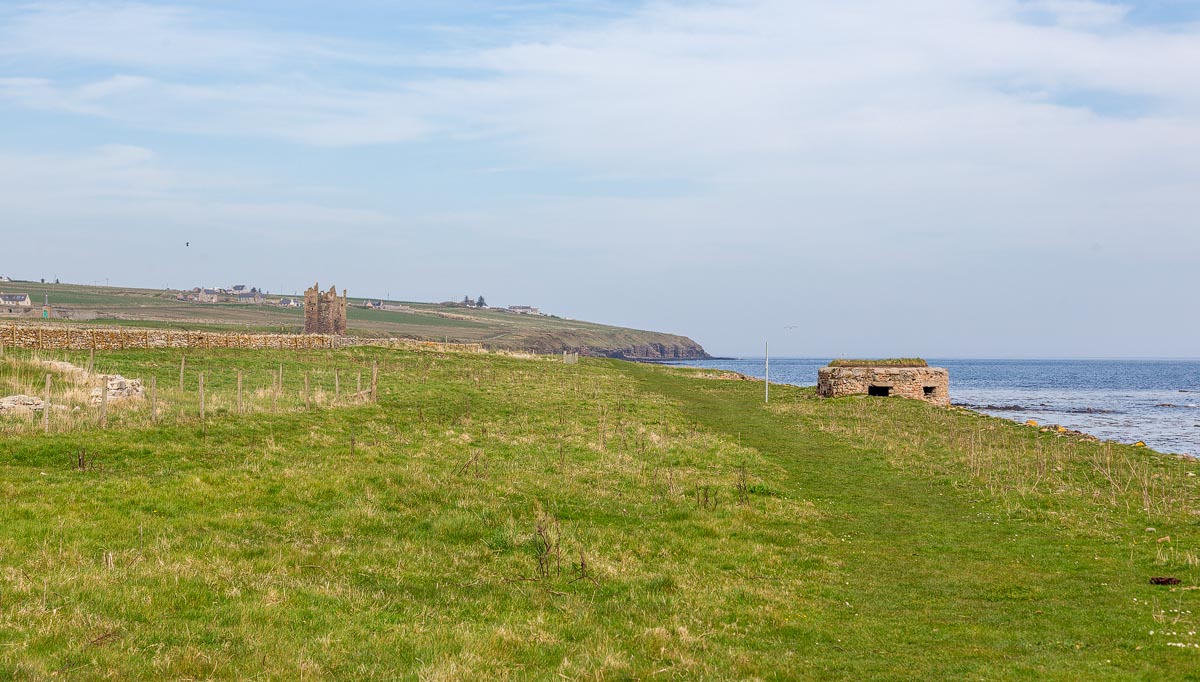 View along the Caithness coast showing Old Keiss Castle in the distance with a WW2 pillbox on the clifftop