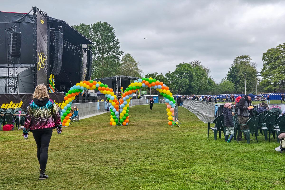 Person walking through colourful balloon archway leading from VIP area towards the main stage