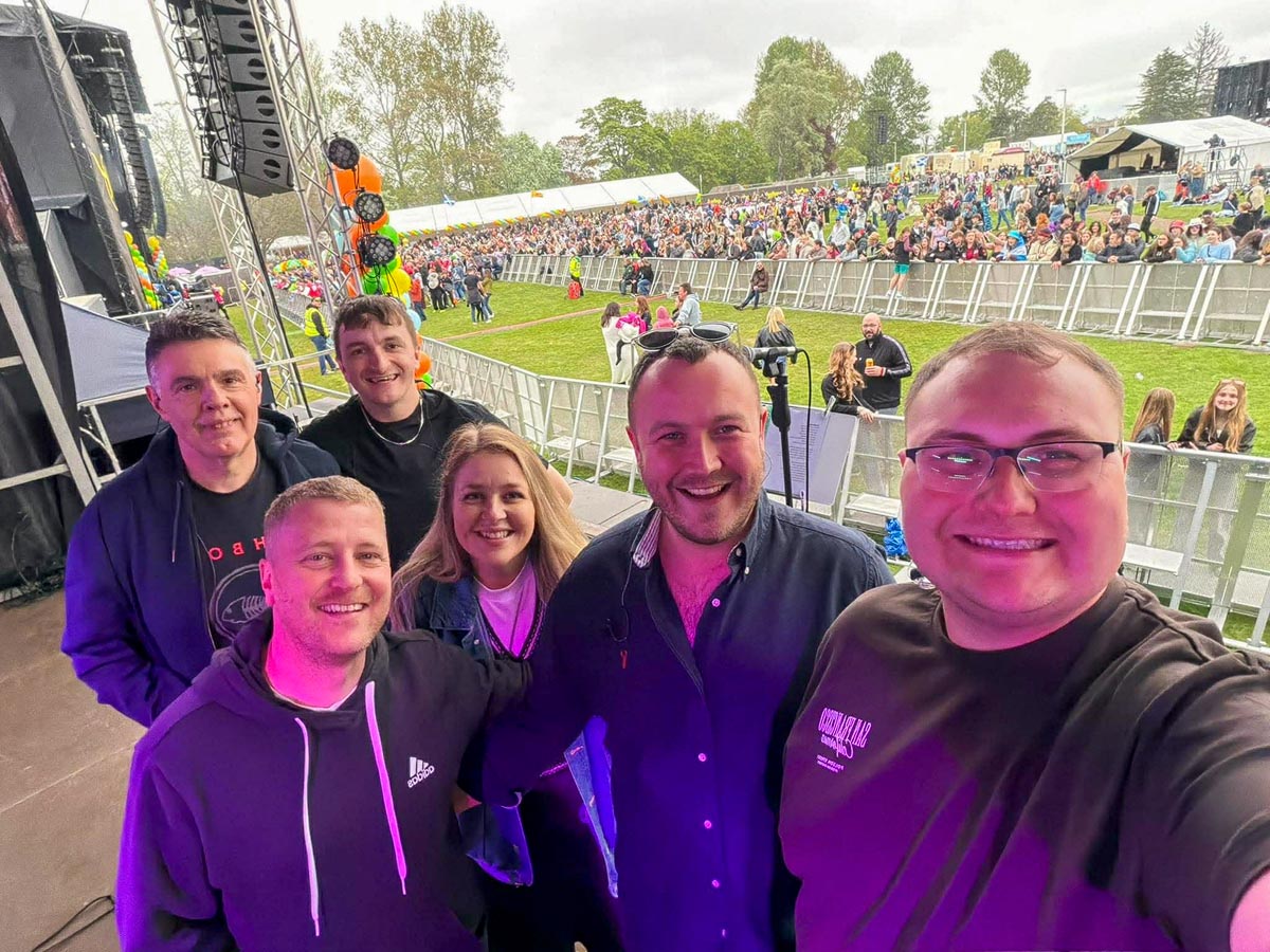 Backstage selfie from members of the band MacTa with crowd visible behind