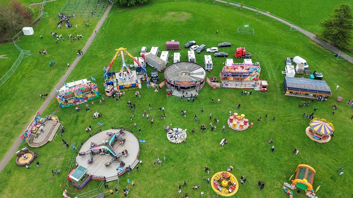 Aerial drone view of the MacMoray funfair at Cooper Park showing dodgems, Fun House, Star Flyer and chair rides