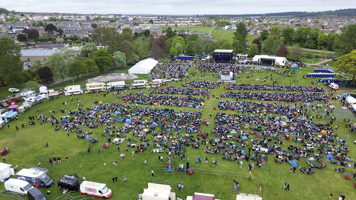 Drone view of MacMoray main stage and crowd with Elgin housing in the background