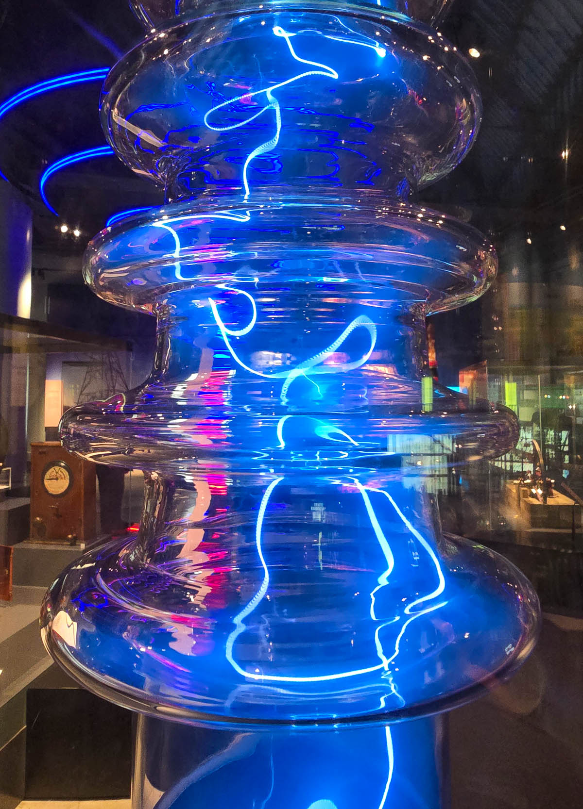 A glowing plasma discharge tube pulsing with vivid blue light in the Science and Technology gallery