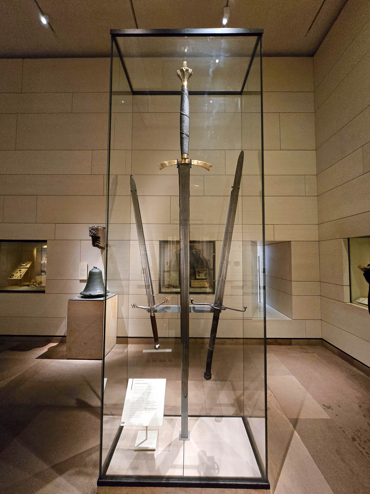 A medieval two-handed claymore and other Scottish swords displayed in a tall glass case at the National Museum of Scotland