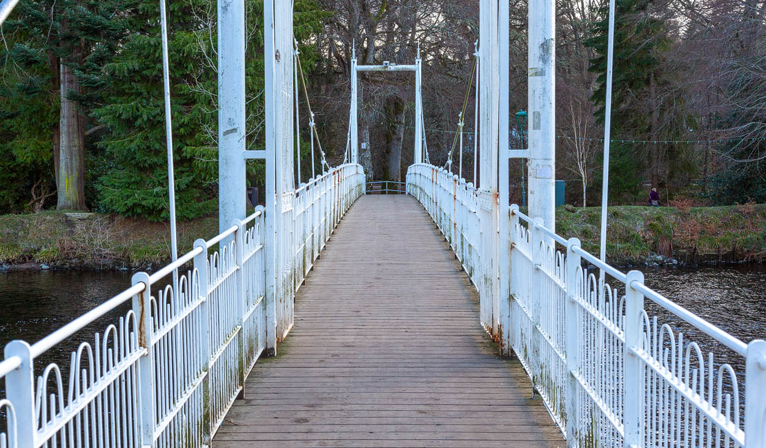 The view down a suspension bridge at Ness Islands.