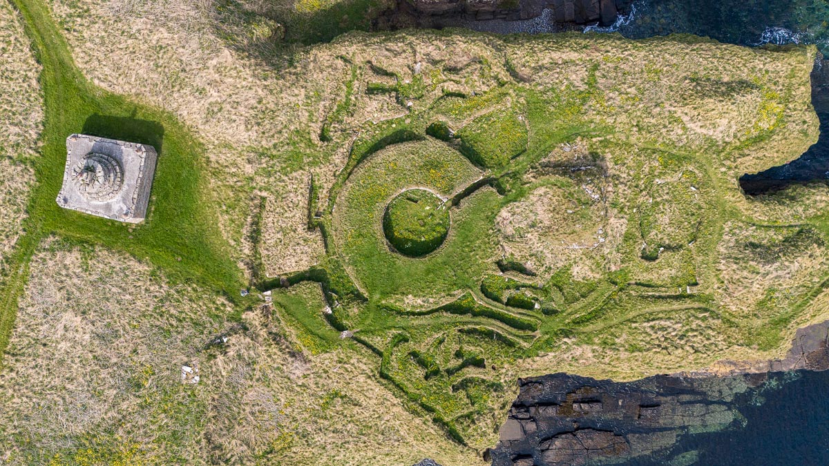 Aerial drone view directly above Nybster Broch showing the circular roundhouse at the centre surrounded by outbuildings and Mervyn’s Tower to the west