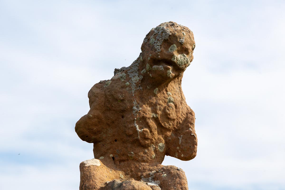 Close-up of a carved grotesque sandstone figure sitting atop Mervyn’s Tower at Nybster Broch
