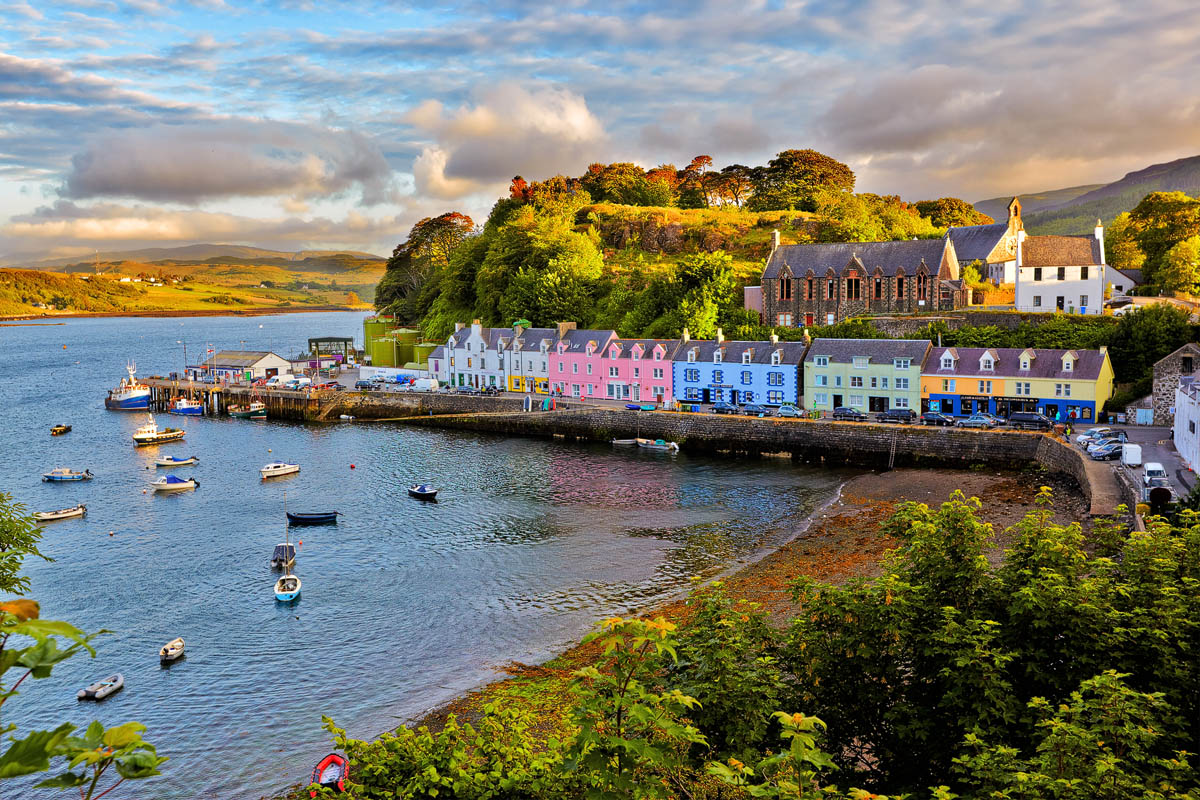 Portree harbour on the Isle of Skye with brightly painted houses reflected in the calm water