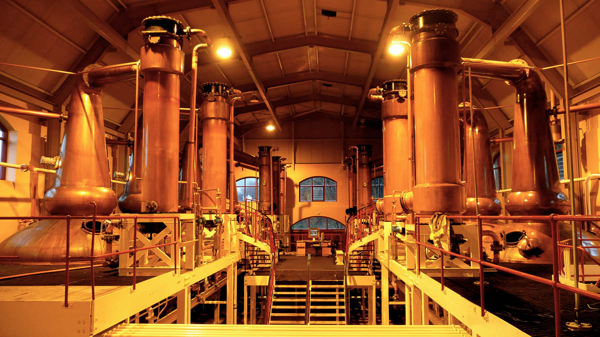 Copper whisky stills inside a Speyside distillery gleaming under warm lighting