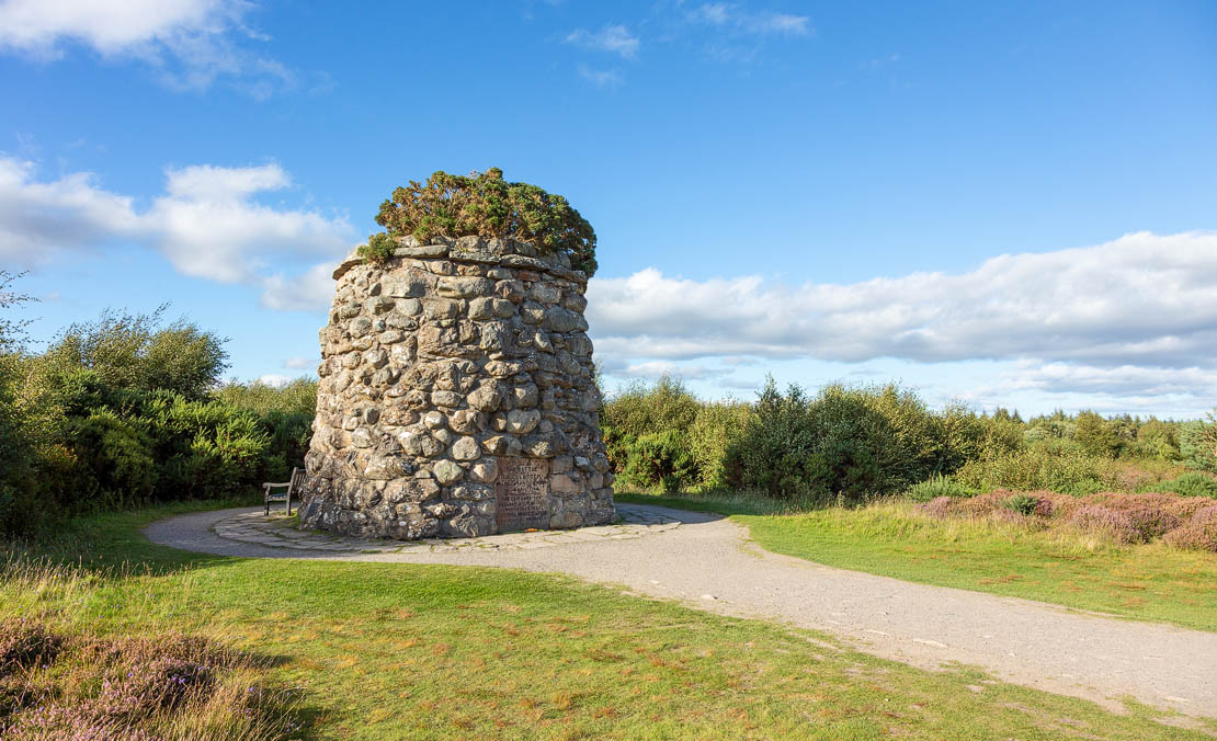 The memorial cairn at Culloden Battlefield on a grey Highland day with heather in the foreground