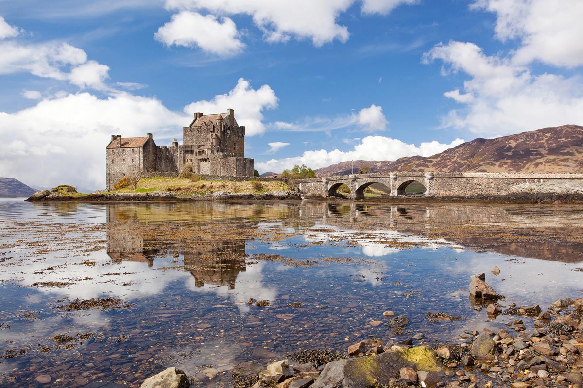Eilean Donan Castle reflected in the calm waters of Loch Duich with mountains in the background
