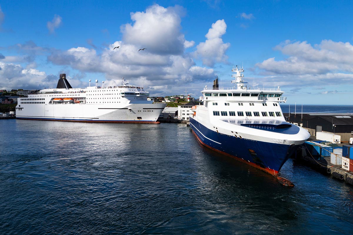 A cruise ship and NorthLink ferry berthed alongside each other in Stromness harbour on a sunny day