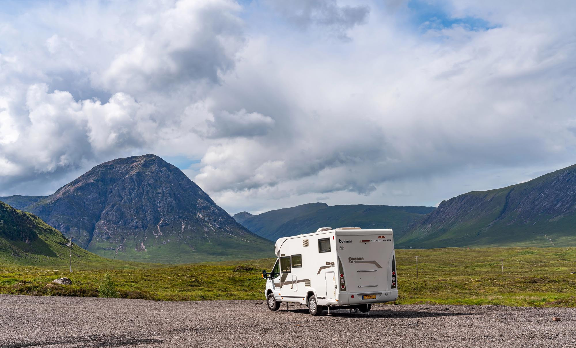 A campervan parked beside a Scottish loch with mountains in the background