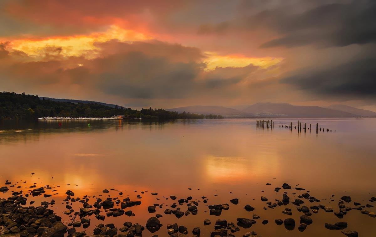 Sunset over a Scottish loch with a campervan silhouetted in the foreground