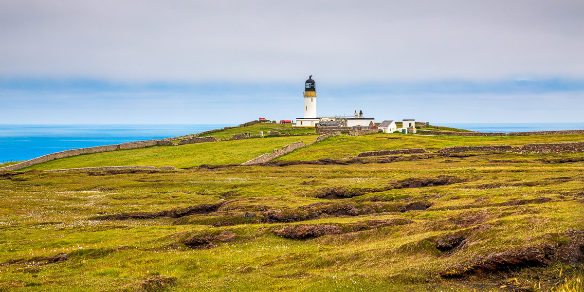 Cape Wrath lighthouse and its walled compound on green moorland above the Atlantic
