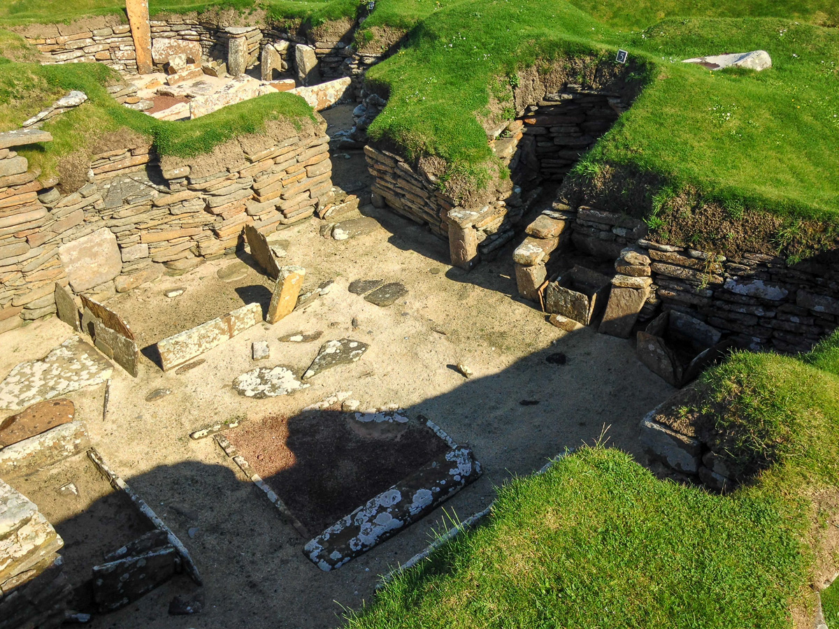 Looking down into a Neolithic house at Skara Brae in Orkney, with its stone hearth, box beds and dresser