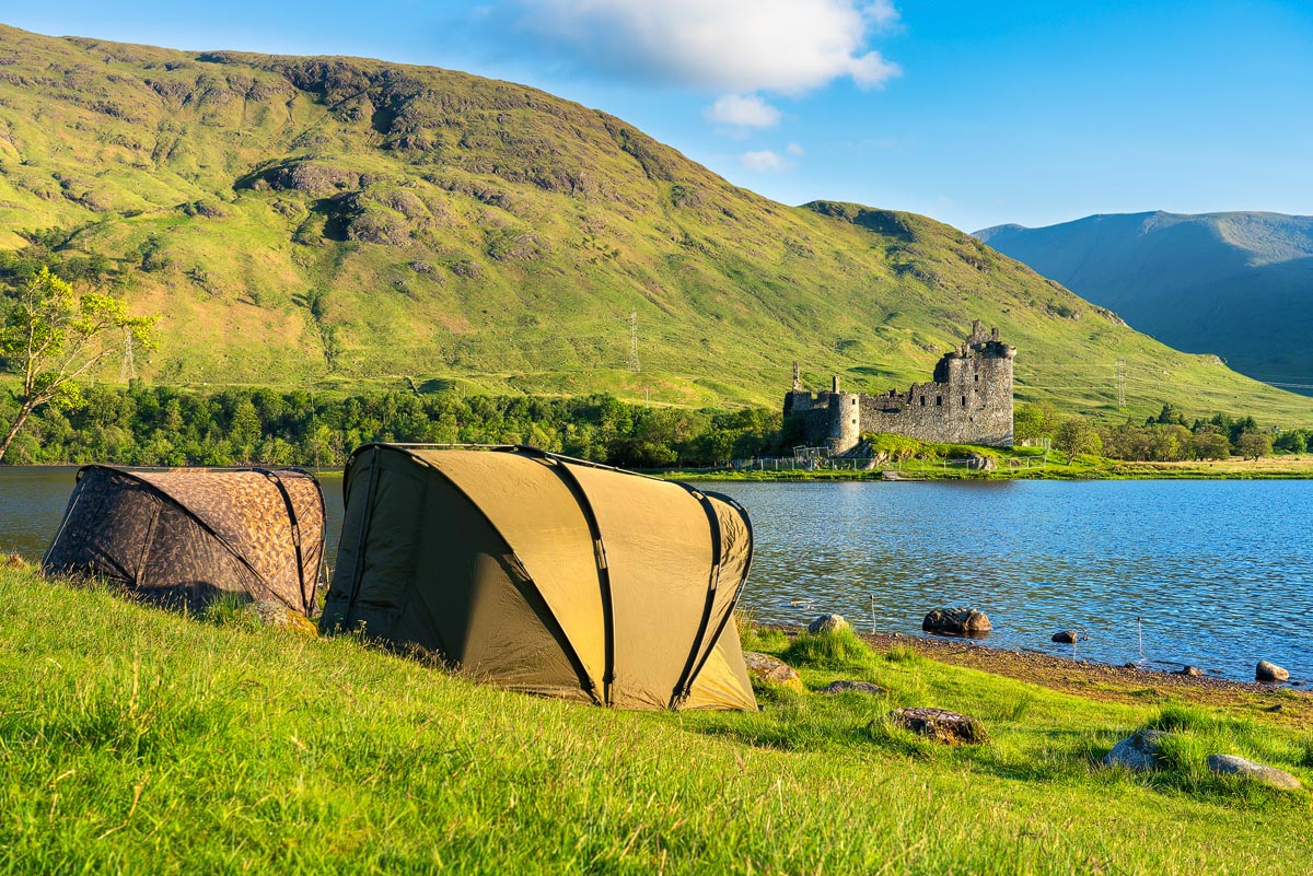Two tents pitched on the shore of Loch Awe with Kilchurn Castle visible across the water