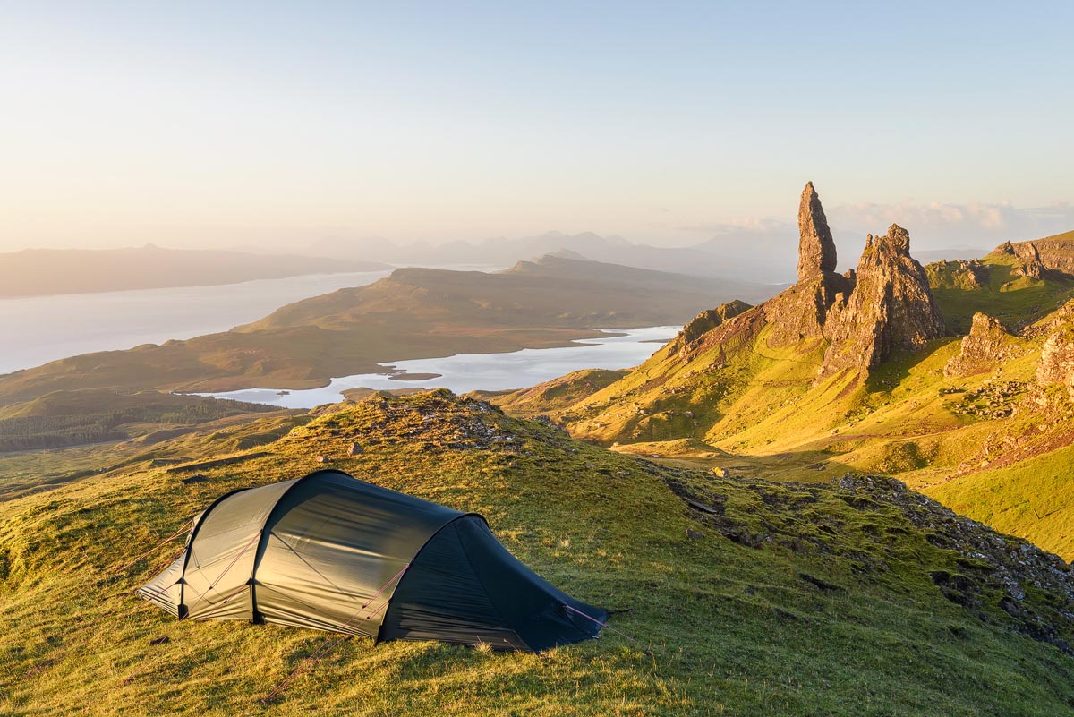 A tent pitched near the Old Man of Storr on the Isle of Skye at sunrise with views over lochs and mountains