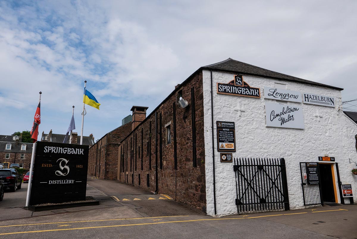 The entrance to Springbank Distillery in Campbeltown showing the Springbank, Longrow and Hazelburn branding on the white-painted wall
