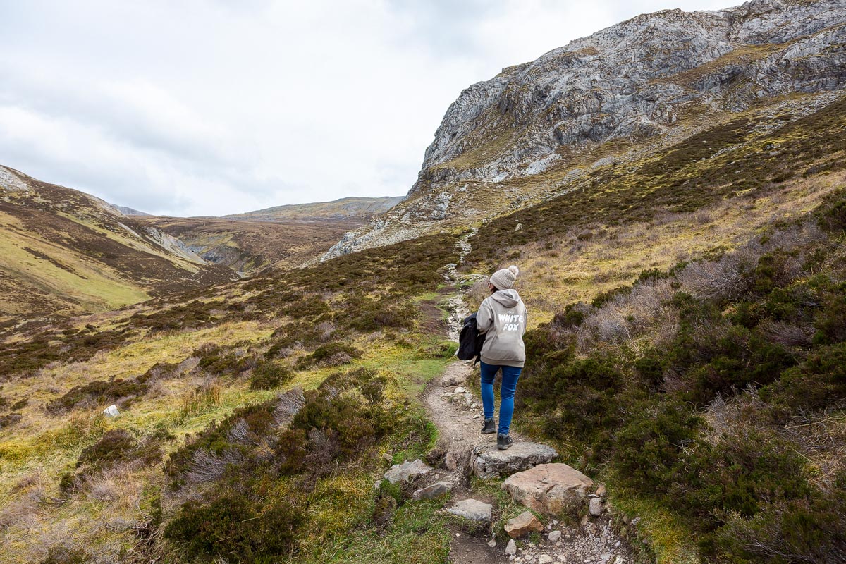 Janette walking towards the limestone cliffs with the sweeping valley and mountains behind her