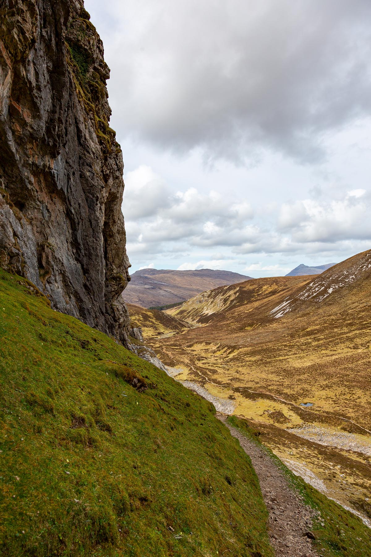 The dramatic vertical cliff face of Creag nan Uamh with the Allt nan Uamh valley and distant mountains below