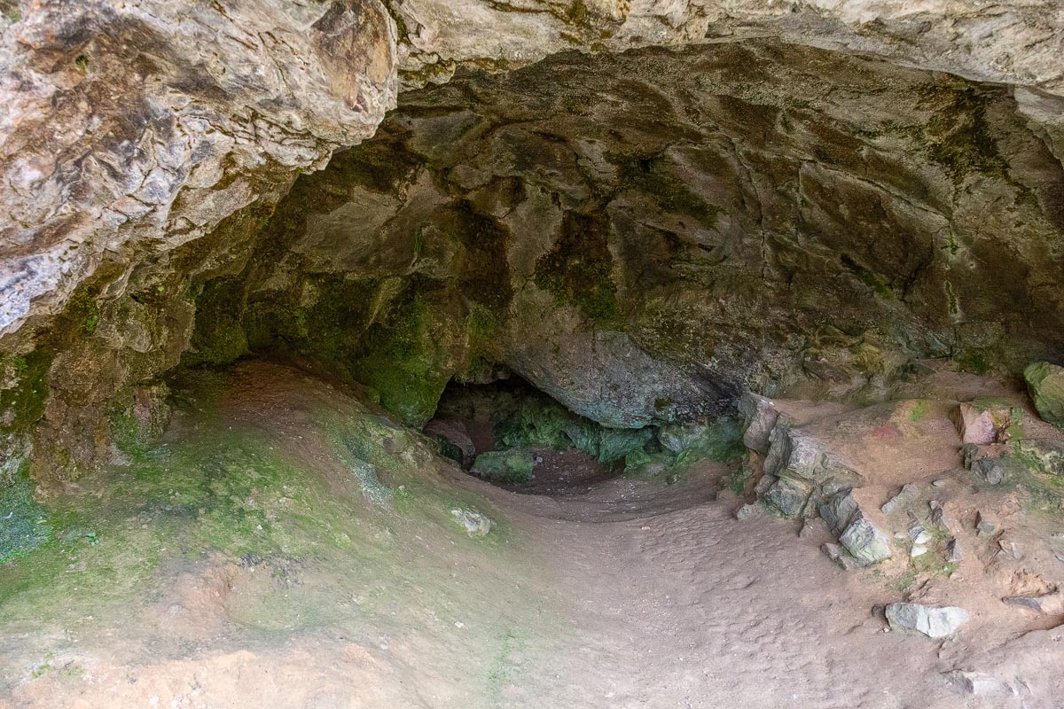 Inside one of the Bone Caves showing the limestone ceiling, muddy floor, and narrow passage leading deeper into the rock