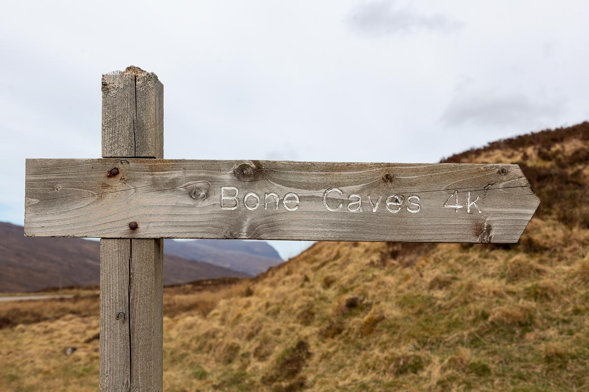 Wooden signpost reading Bone Caves 4k pointing towards the walking path