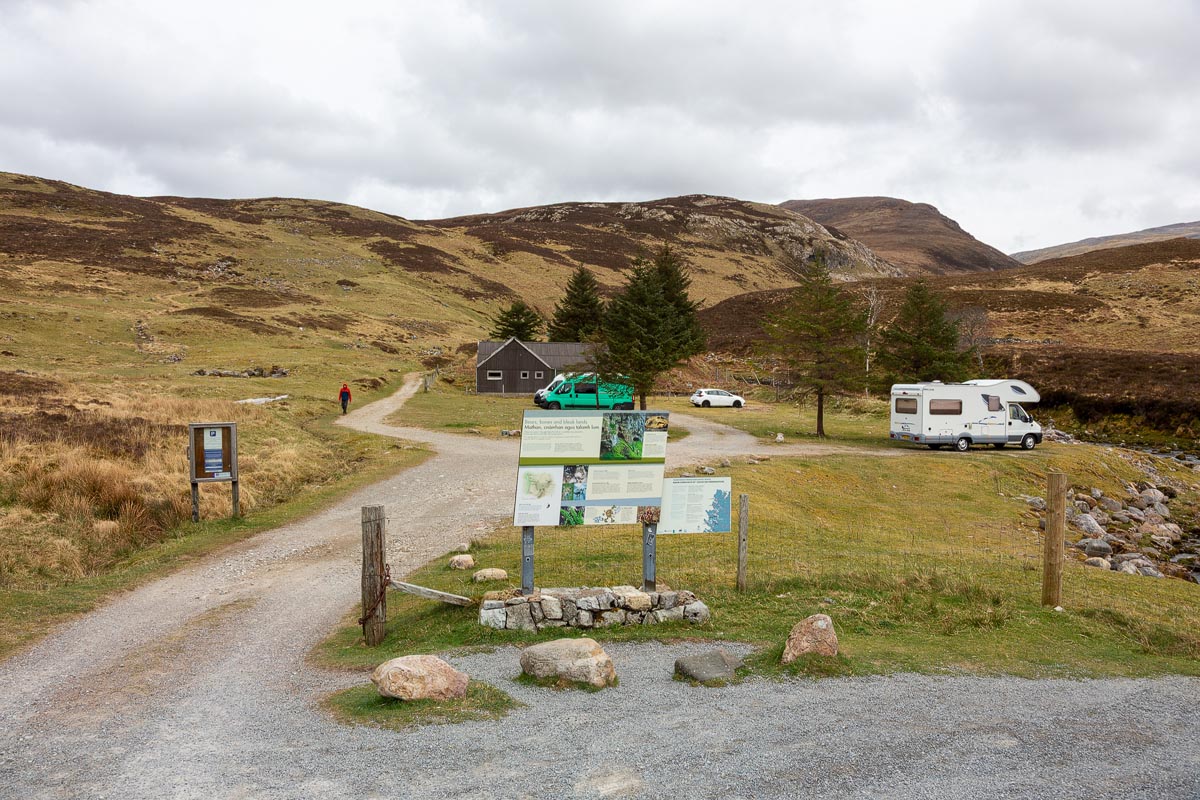 The trailhead for the Bone Caves walk showing information boards, a gate, and a building with the path leading into the glen