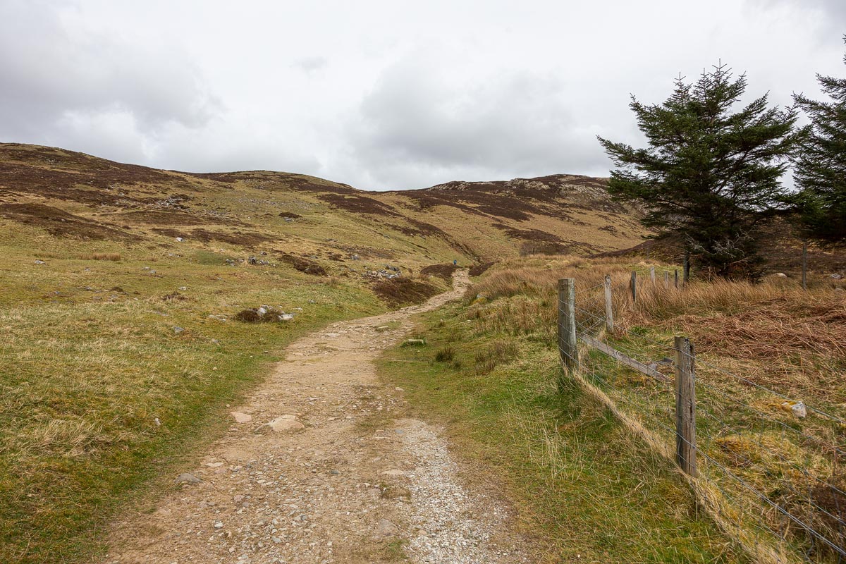 The gravel path heading into the glen towards the Bone Caves with heather-covered hills on either side