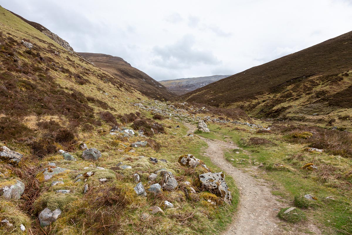 The path winding through boulder-strewn terrain in the Allt nan Uamh glen with limestone cliffs visible ahead