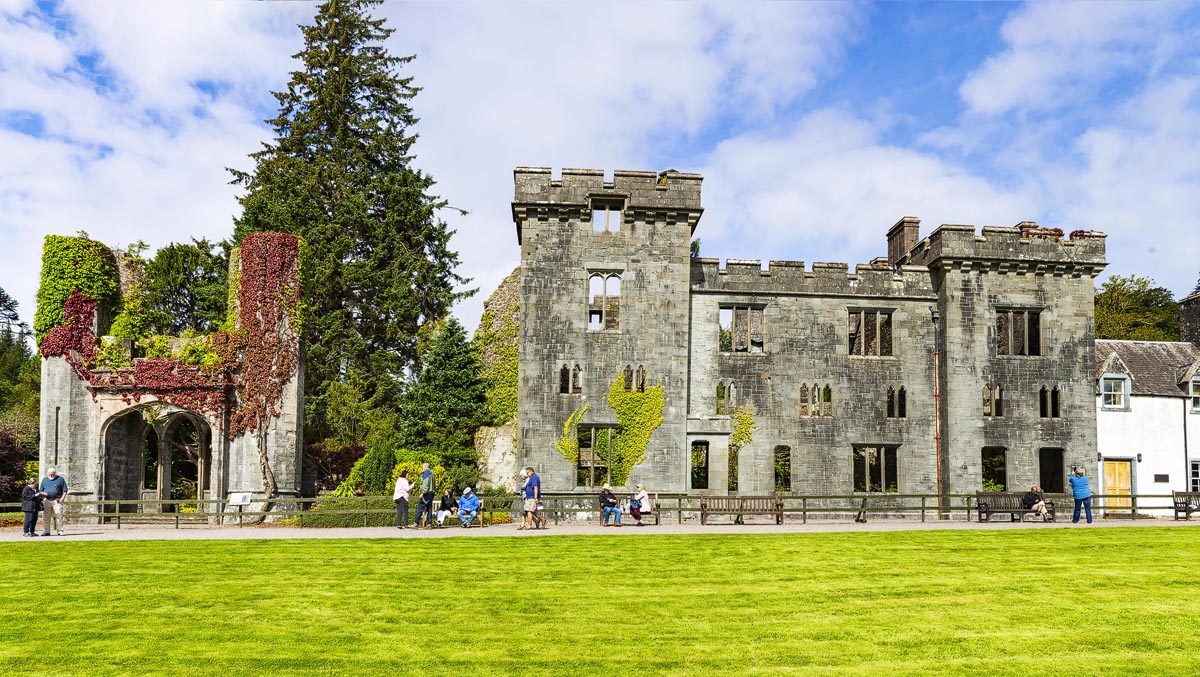 The ivy-covered ruins of Armadale Castle on the Sleat peninsula with visitors on the manicured lawn