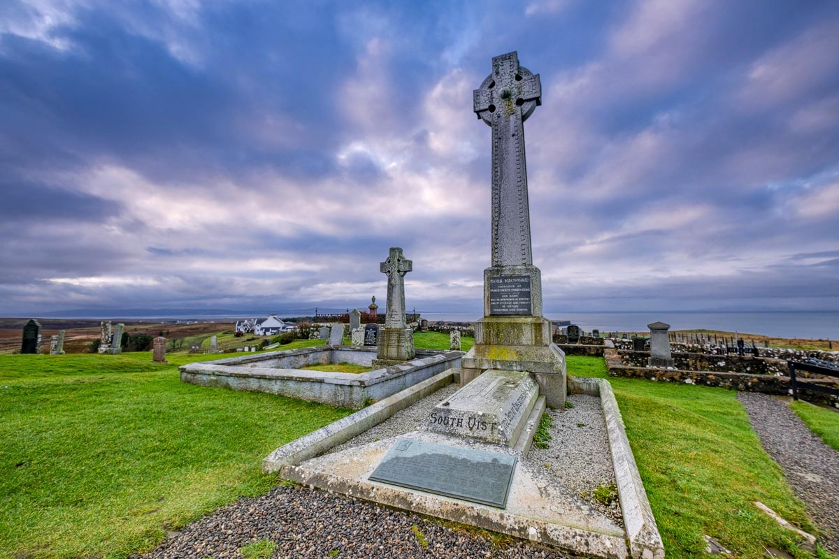 The tall Celtic cross memorial to Flora MacDonald in the churchyard at Kilmuir on the Isle of Skye with dramatic sky