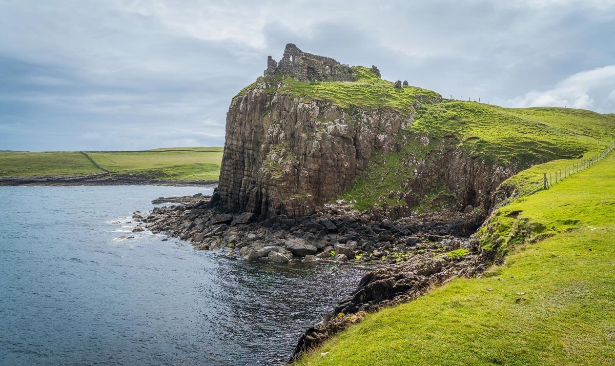 The ruined walls of Duntulm Castle perched on a dramatic cliff top above the sea on the Isle of Skye