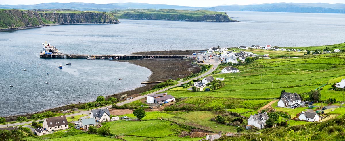Elevated view of Uig village and ferry terminal on the Isle of Skye with green crofting land and surrounding cliffs