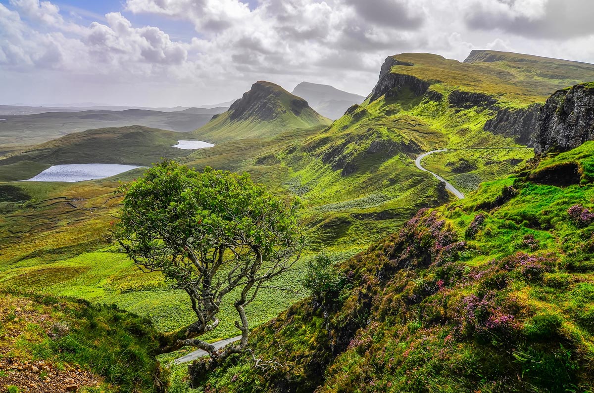 The sweeping green landscape of the Quiraing on the Trotternish Peninsula with lochs, winding road and heather-covered hills