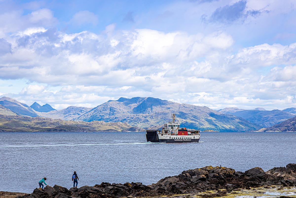 A Caledonian MacBrayne ferry crossing the water towards the Isle of Skye with the Scottish mainland mountains in the background