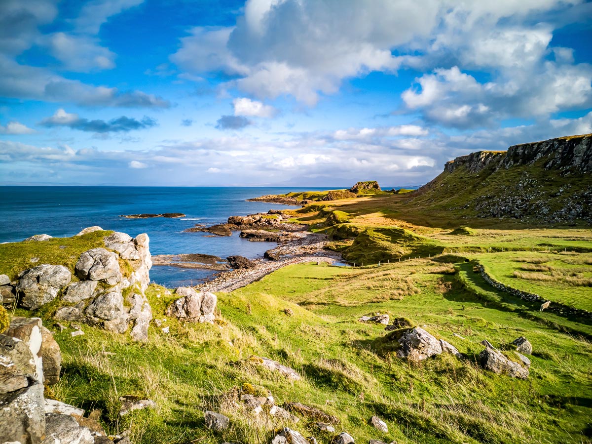 The rugged green coastline at Brother's Point on the Isle of Skye with rocky shoreline and dramatic cliff backdrop