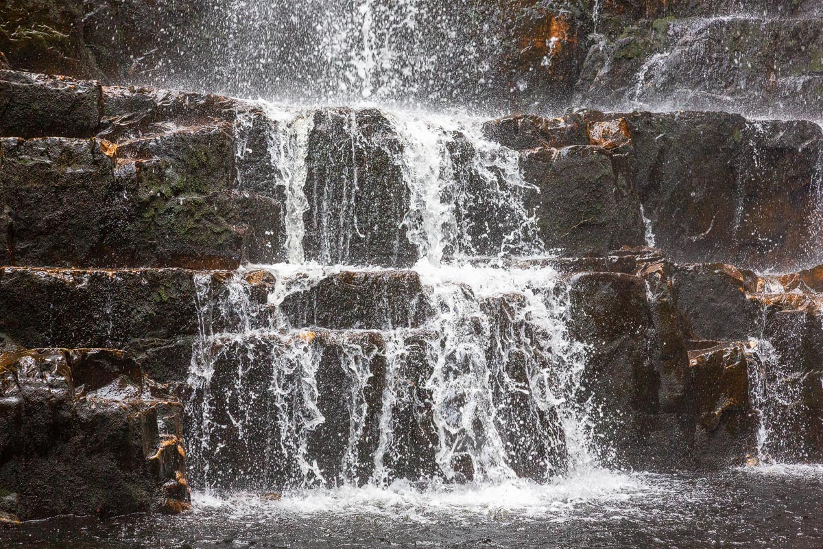 Close-up of water cascading over stepped rock formations at the base of Wailing Widow Falls