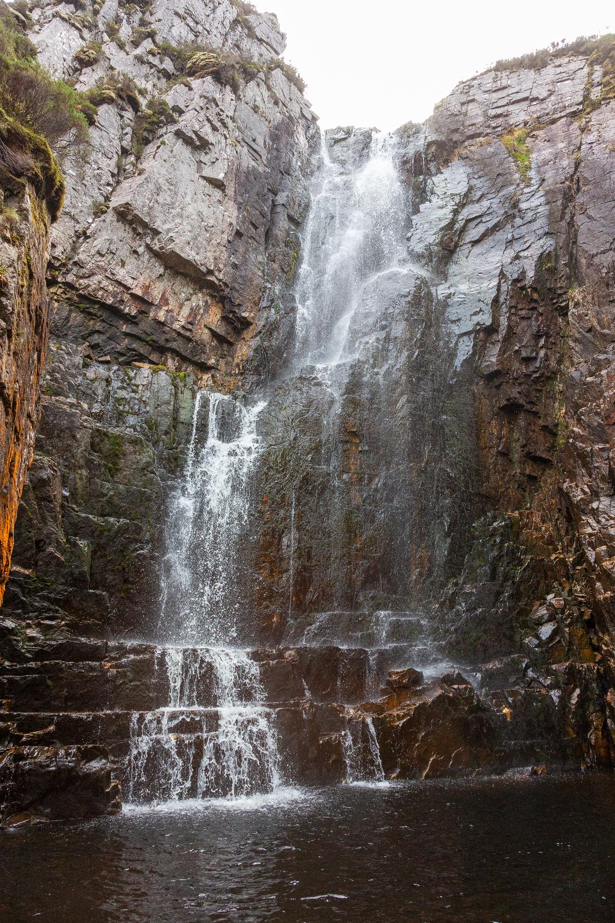 Wailing Widow Falls cascading down layered rock into a dark plunge pool