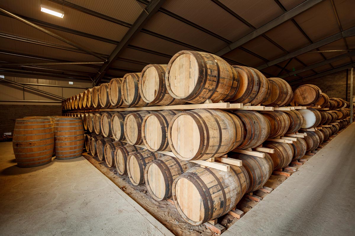 Oak whisky casks stacked three high on wooden rails inside a traditional dunnage warehouse